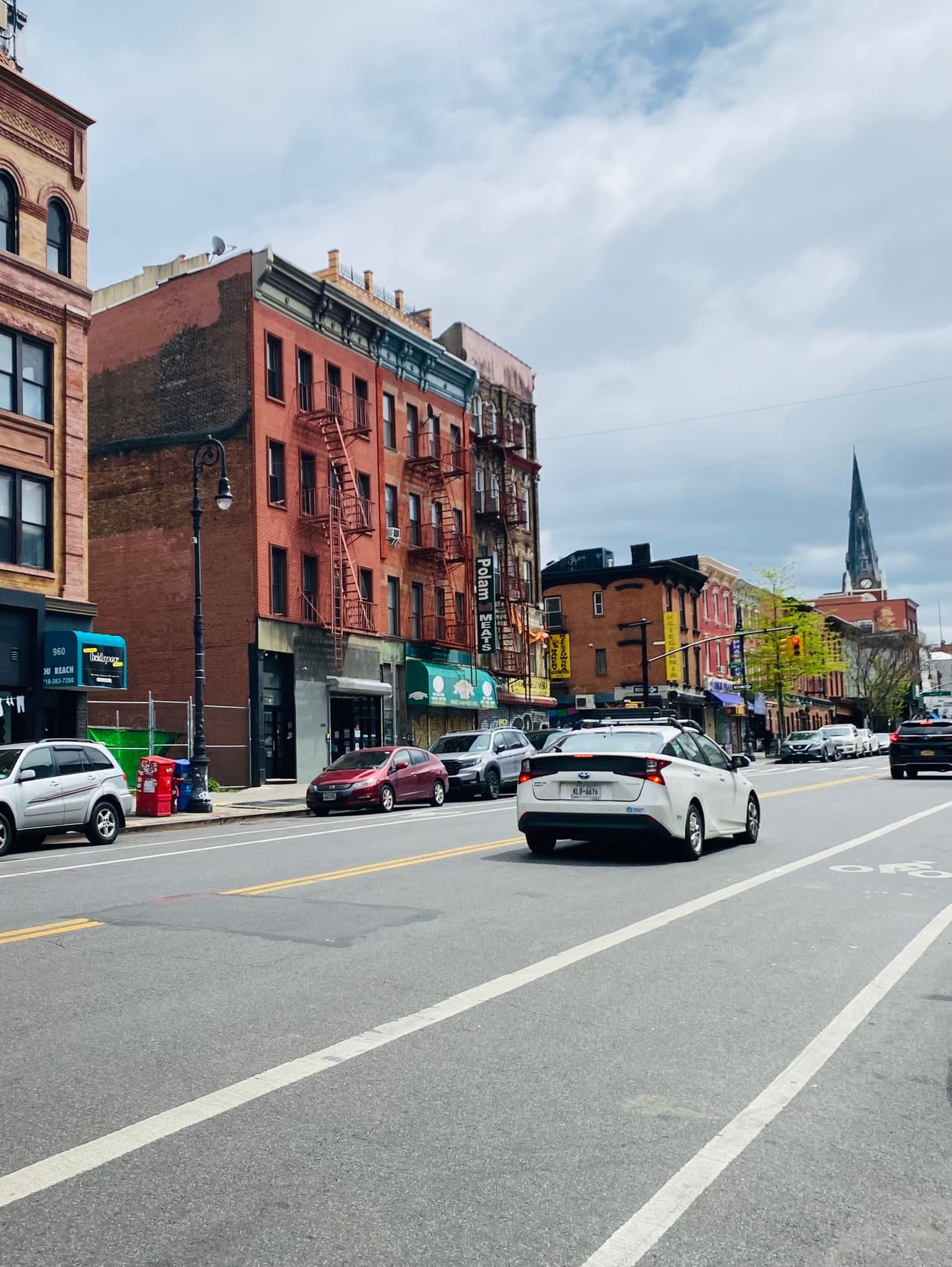 Car driving on an urban street between brick buildings
