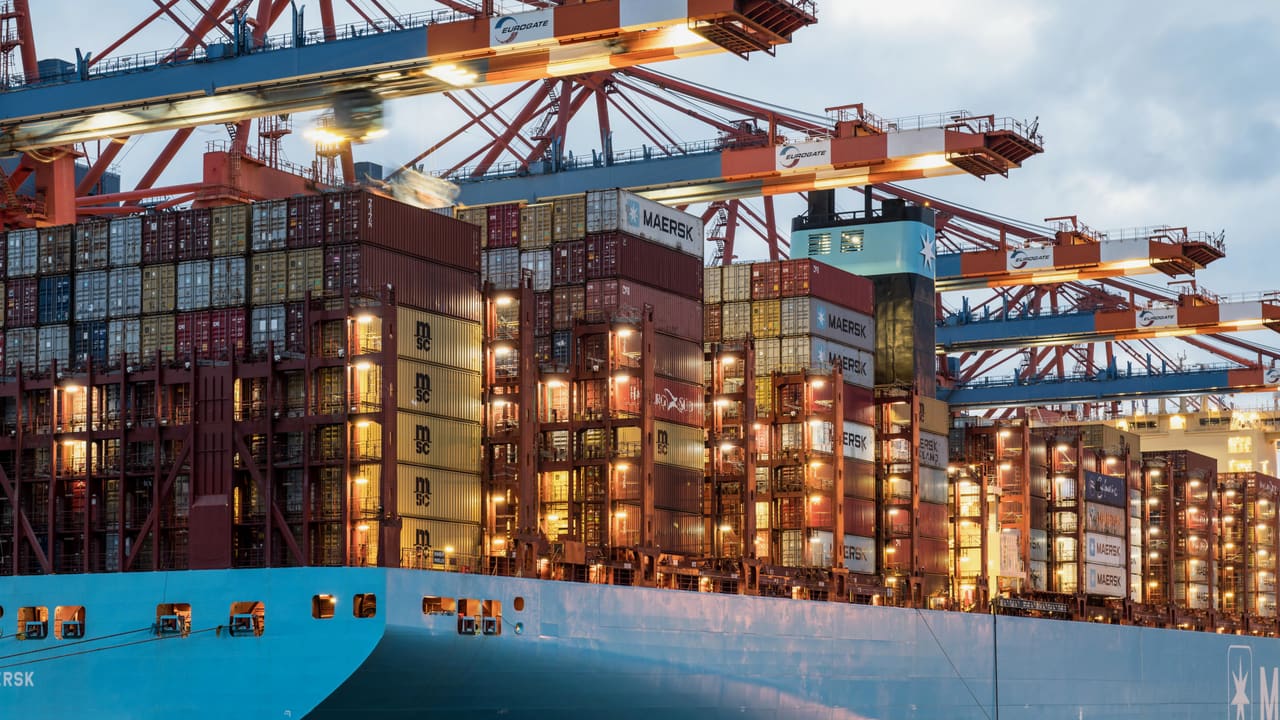 Container ship under cranes at a busy port terminal